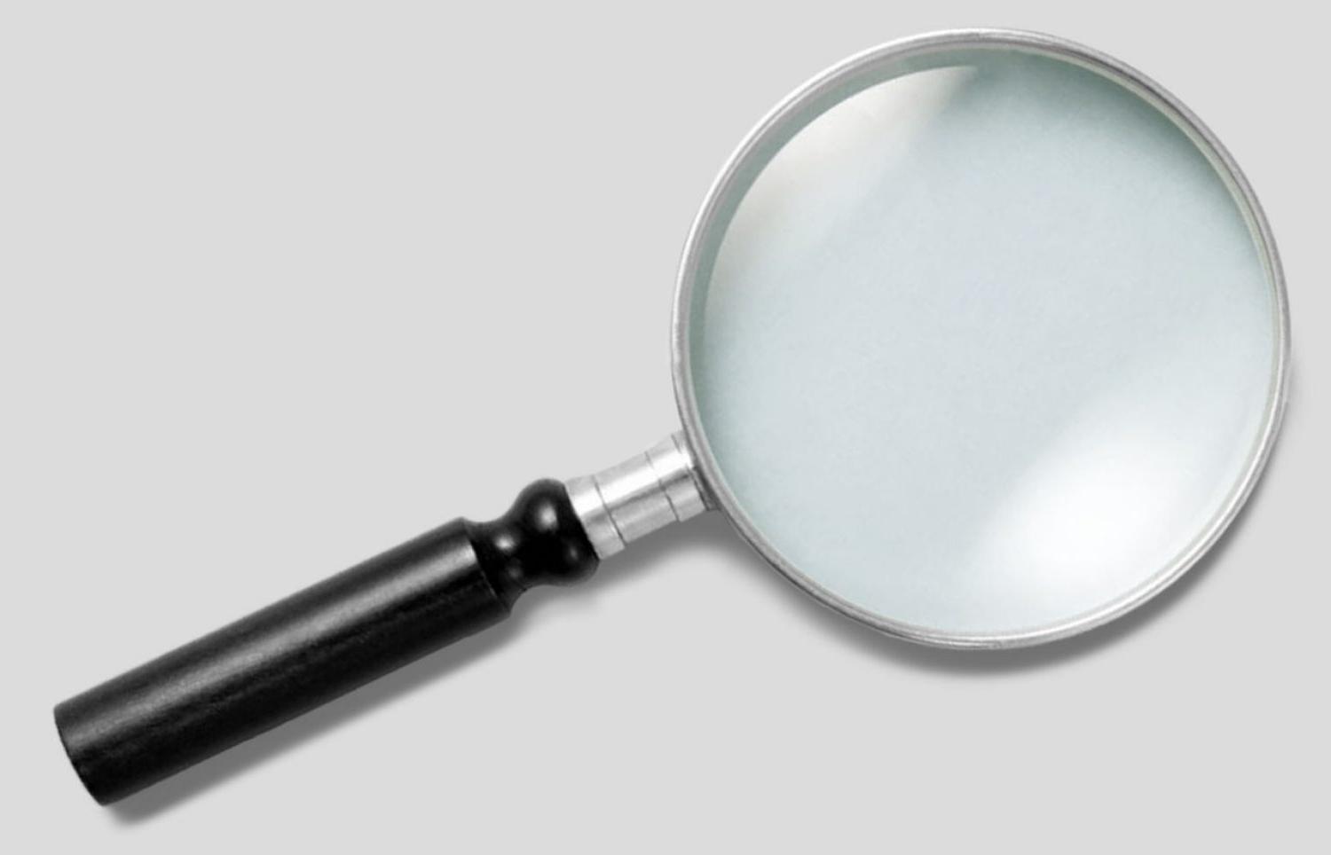 A magnifying glass lays on a solid gray background