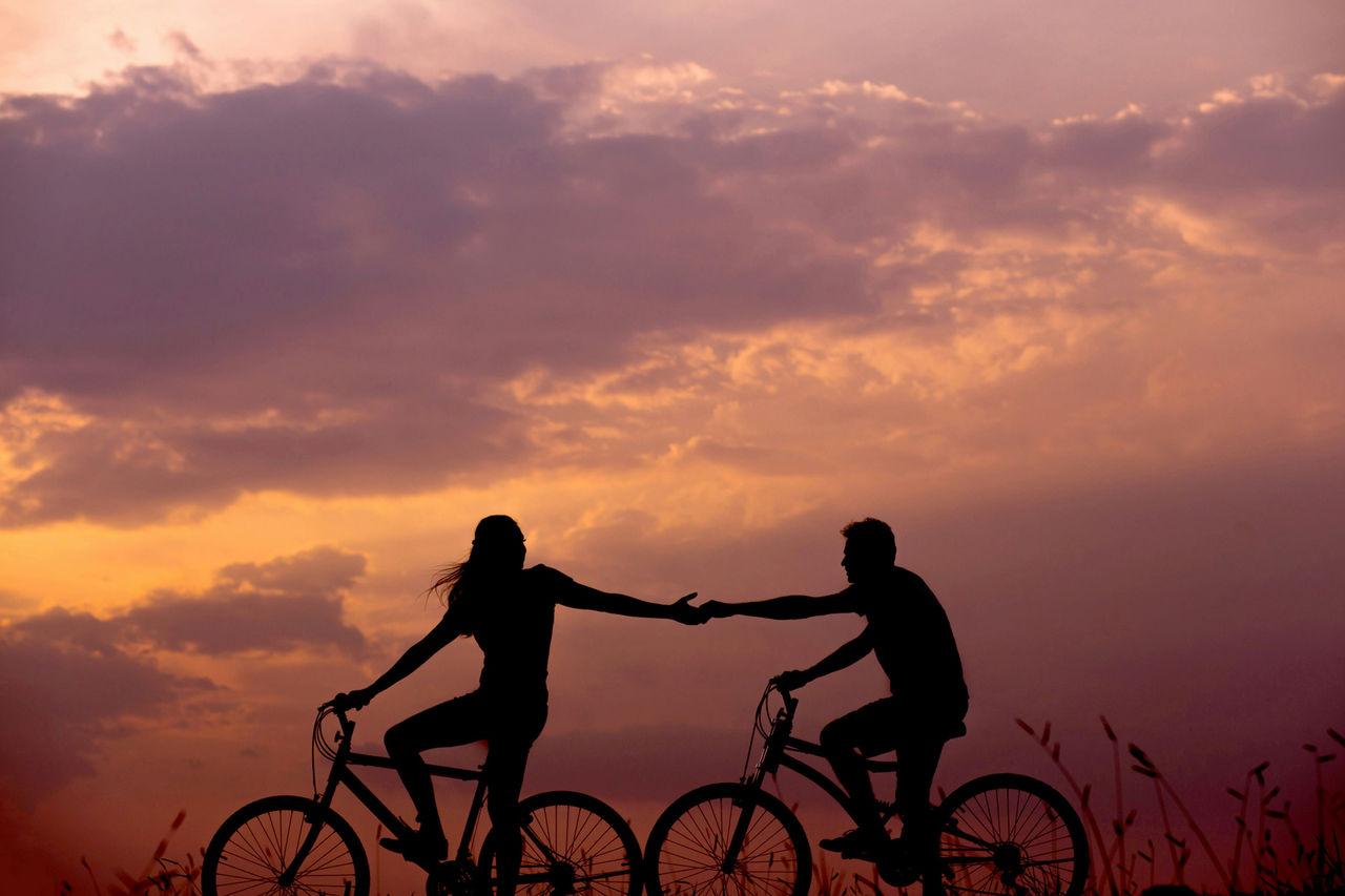 partners reaching for each others hands on a bike