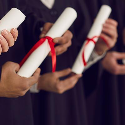 在毕业典礼上，身穿黑色长袍的大学生手持传统的毕业证. 快乐的毕业生手里拿着证书，庆祝获得学位的人生里程碑